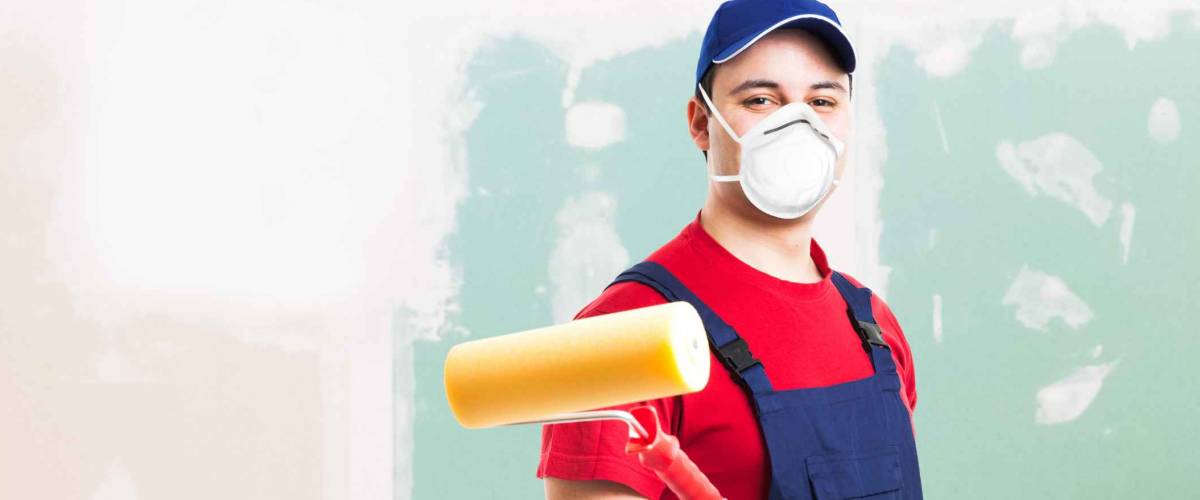 Portrait of a masked painter at work in an apartment