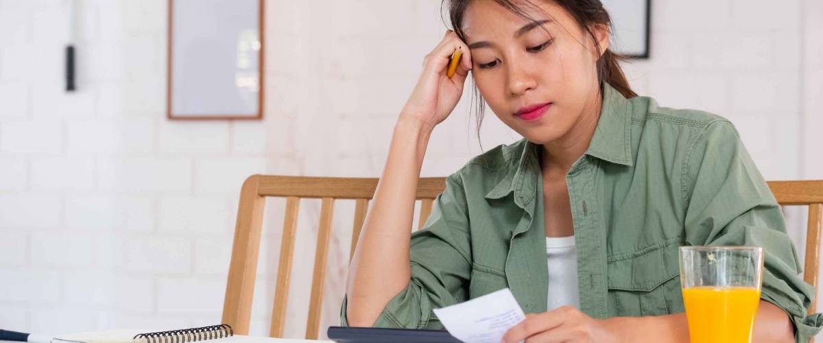 Stressed Asian woman serious and argument when calculate home financial bill budget on table in kitchen at new house