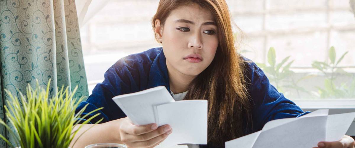 stressed young asian woman trying to find money to pay credit card debt.