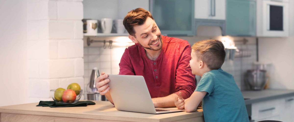 Little boy and his dad using laptop at home