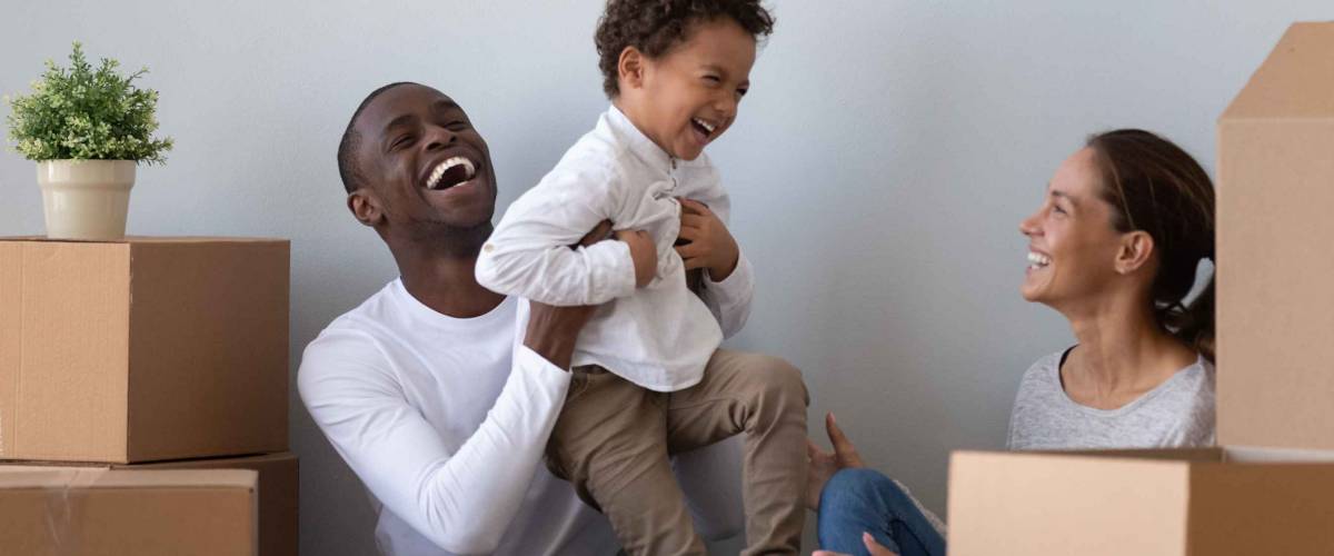 Happy family laughs surrounded by boxes.
