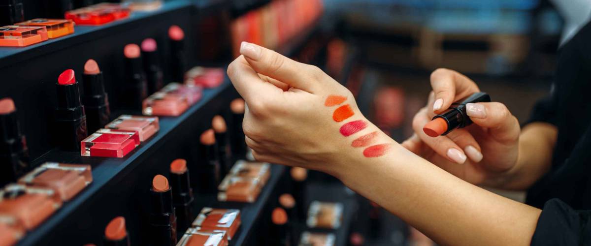 Female customer testing lipstick in make-up shop