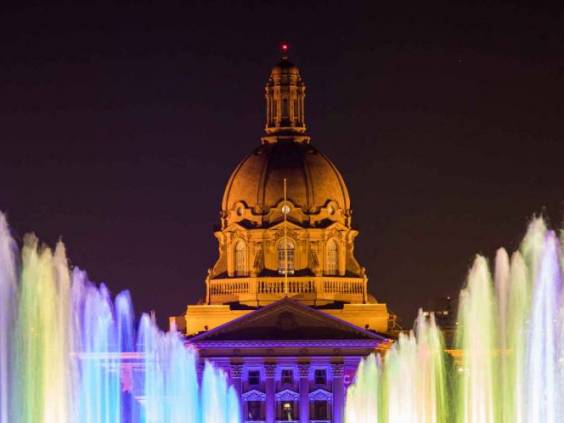 Colorful fountains illuminate a plaza in Downtown Edmonton, Canada, with Alberta's Legislature Building in the background.