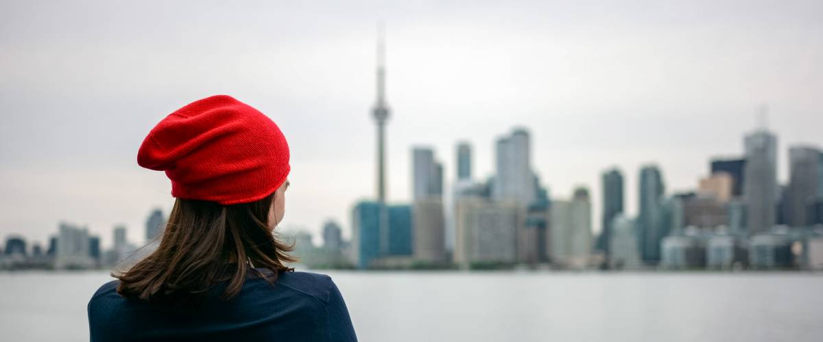 Woman looking at Toronto skyline with CN tower in background over lake