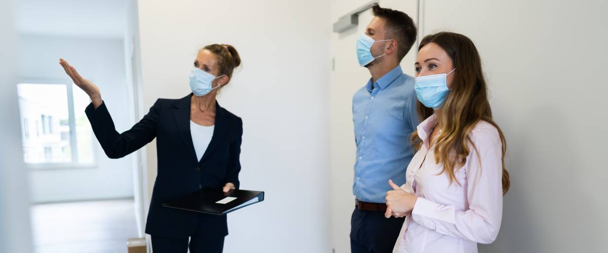 Couple looking at house with realtor, all wearing face masks due to pandemic