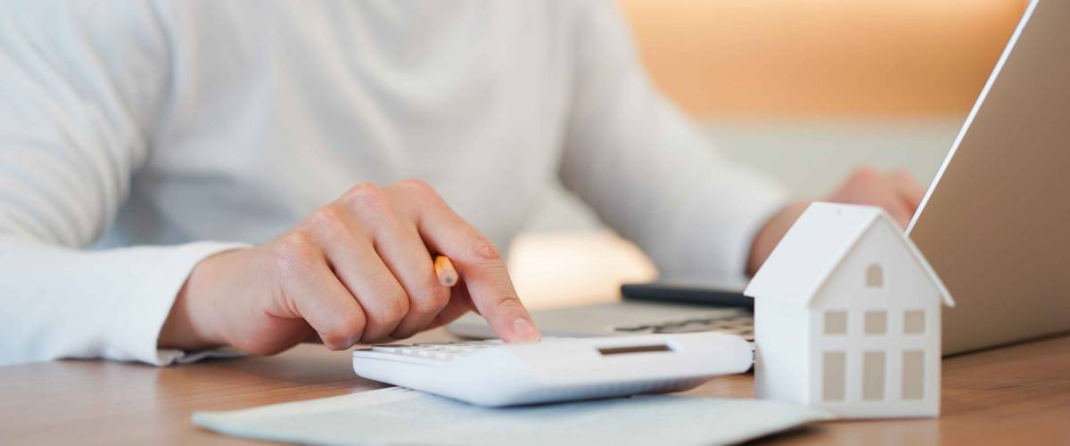close up young man hand press on calculator to check and summary expense of home loan mortgage for refinance plan , people lifestyle concept