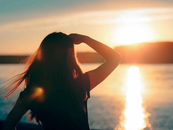 Happy Hopeful Woman Looking at the Sunset by the Sea. Silhouette of a dreamer girl looking hopeful at the horizon