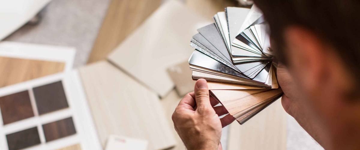 Man seen from behind going through flooring samples
