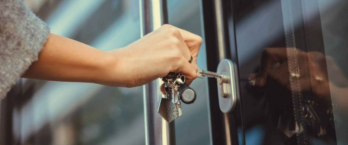 Close up of woman unlocking entrance door with a key. Person using key and locking apartment door.