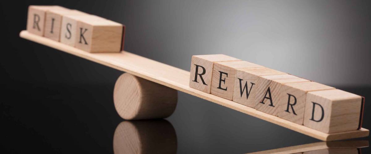 Close-up Of A Wooden Seesaw Showing Imbalance Between Risk And Reward On Grey Background