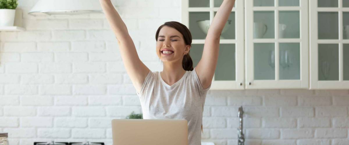 Young attractive woman exulting using calculator and laptop for calculating finance rates looking at screen.