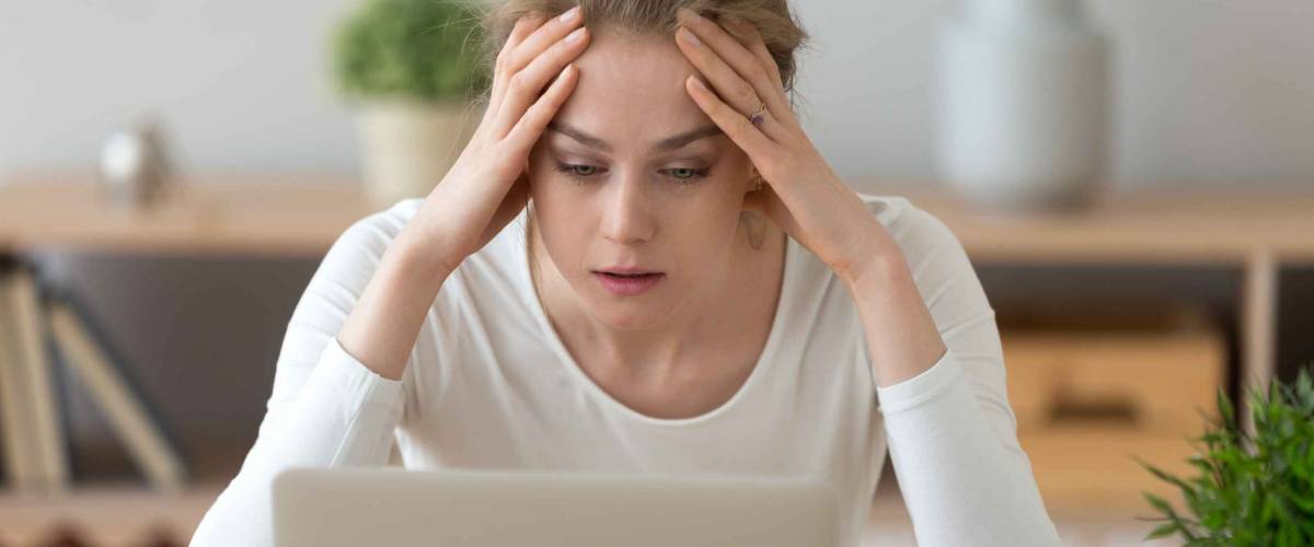 Stressed frustrated young woman student looking at laptop