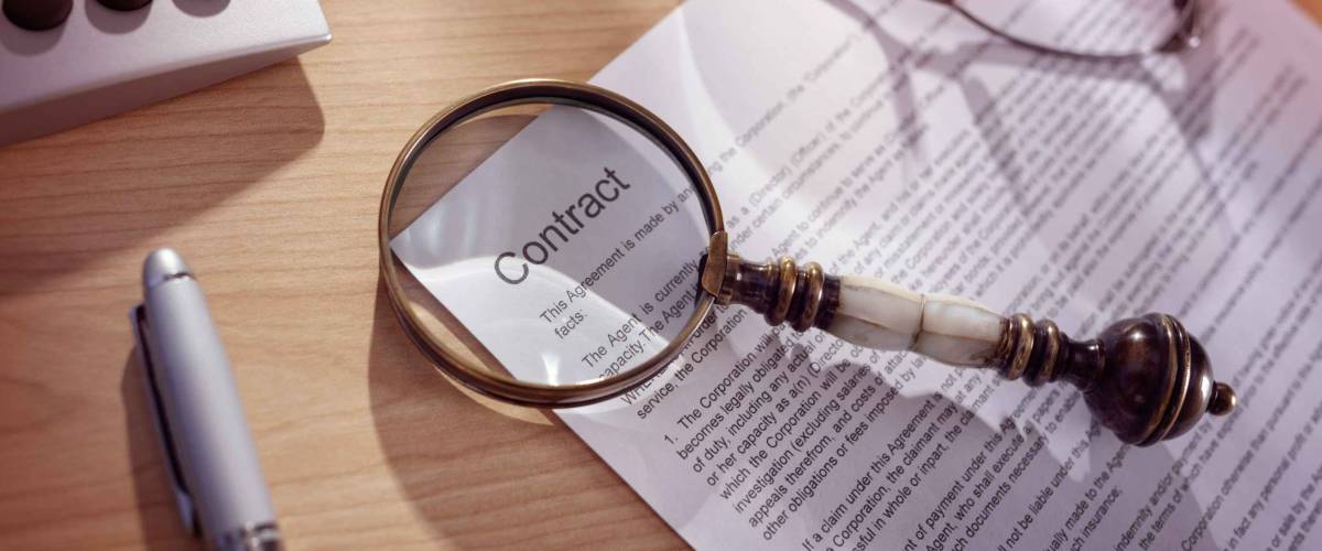 Magnifying glass examining and signing a legal contract document