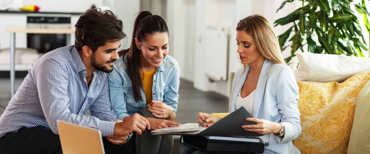 Woman shows young couple something inside folder