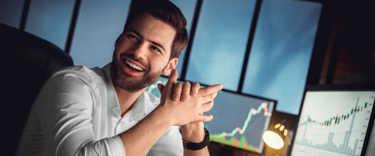 Young male trader at office work concept sitting looking aside cheerful