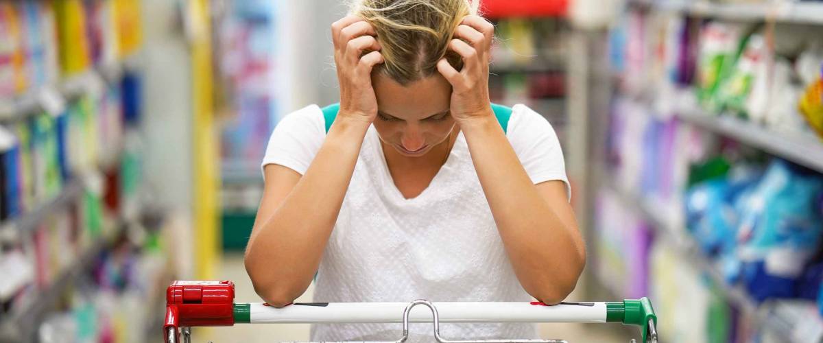 Upset woman in a supermarket with an empty shopping trolley. Crises, rising prices for goods and products. Woman shopping at the supermarket.