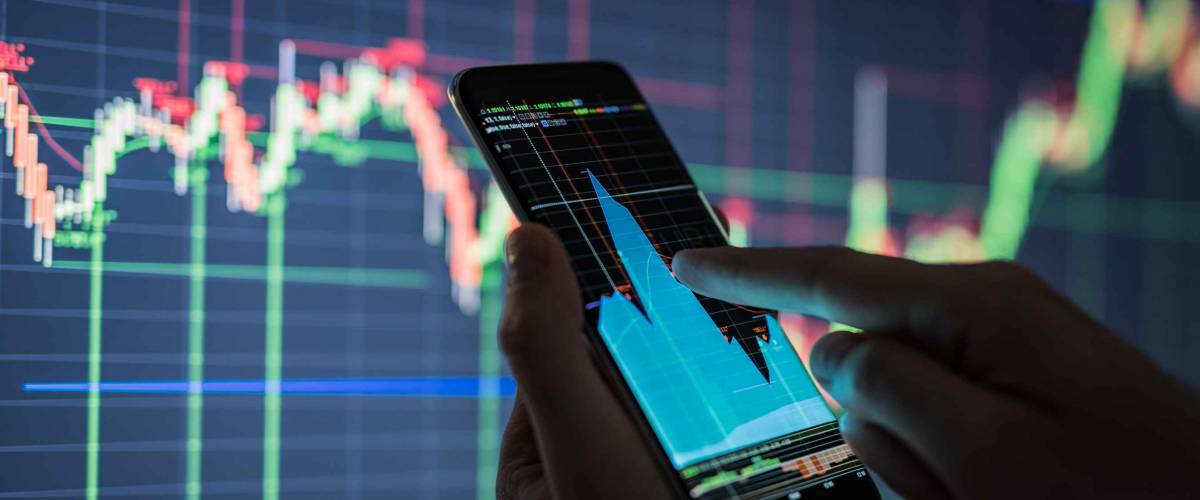 Businessman checking stock market data. He using a mobile phone. Analysis economy data on forex earn graph.