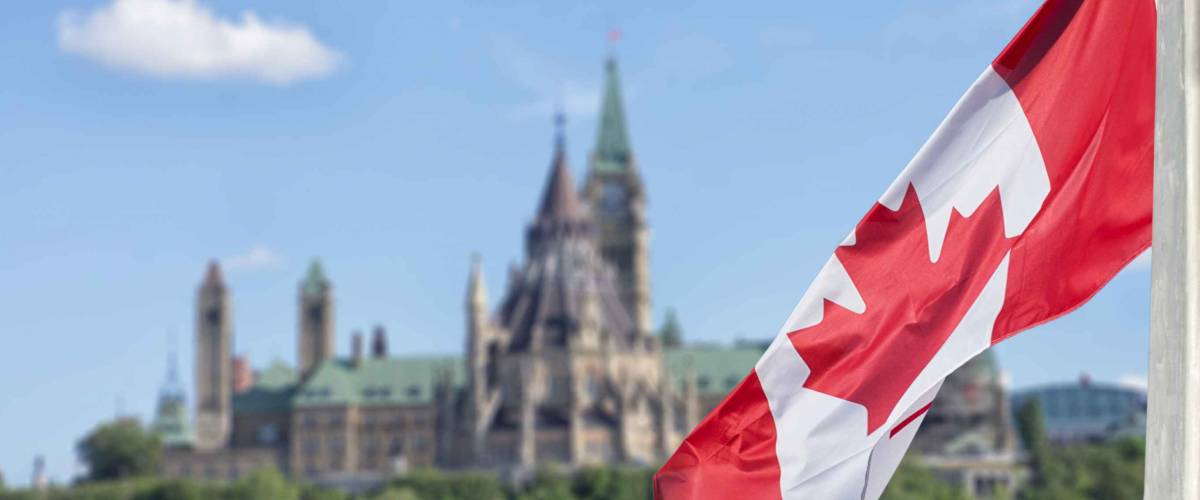 Canadian flag waving with Parliament Buildings hill and Library in the background