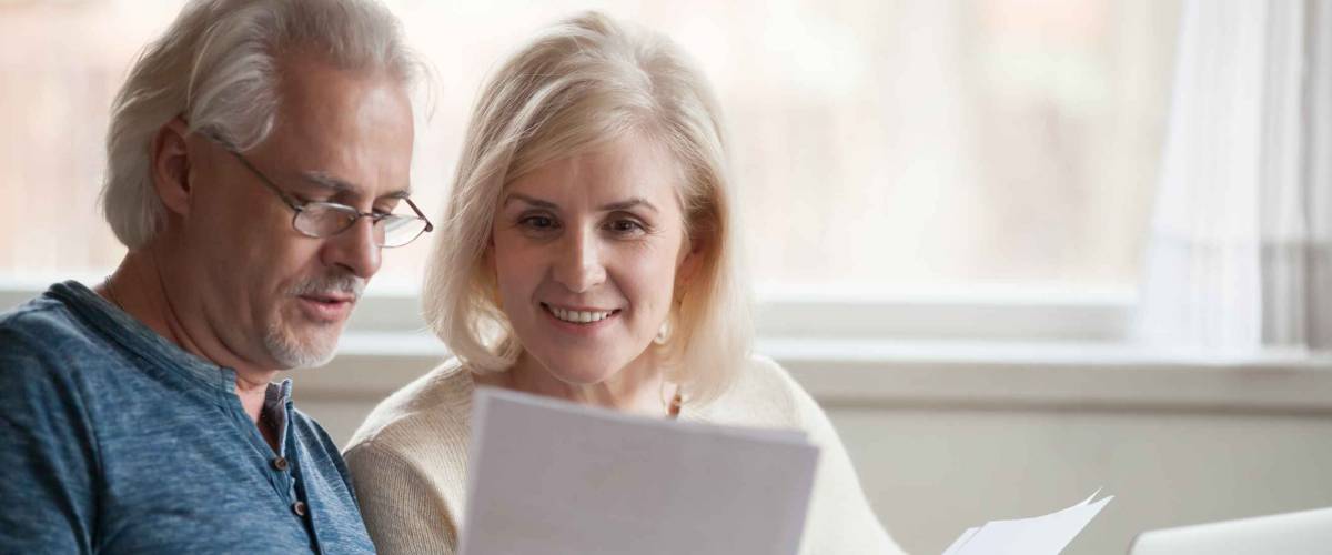 Happy old middle aged couple reading good news in document