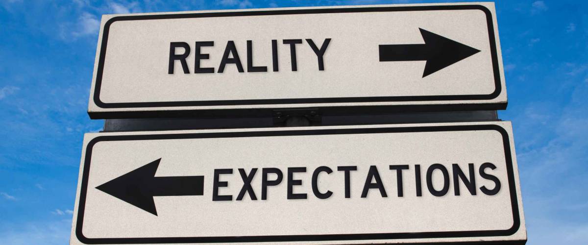 Reality vs expectation. White two street signs with arrow on metal pole with word. Directional road. Crossroads Road Sign, Two Arrow. Blue sky background. Two way road sign with text.