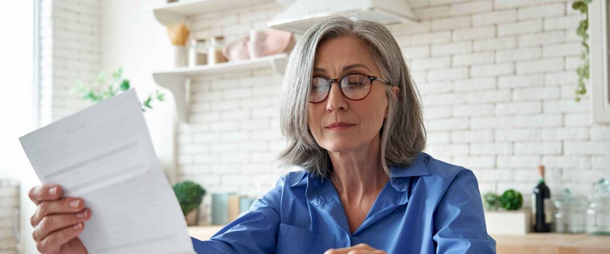 Senior mature business woman holding paper bill.