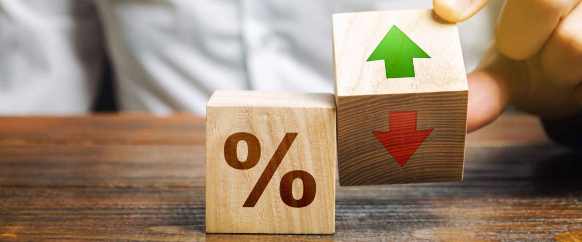 Businessman holds wooden blocks with percent and up or down arrow. Mortgage and loan rates. Interest rate, stocks, ranking. Business and finance concept.