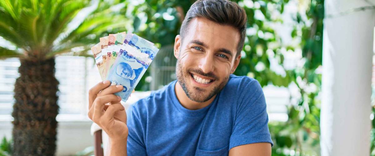 Young hispanic man smiling happy holding Canadian dollars banknotes at the terrace.