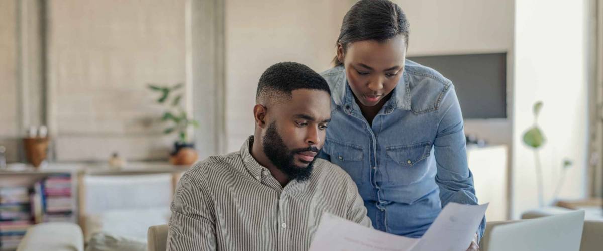 Young couple going over bills and doing online banking at their dining room table at home