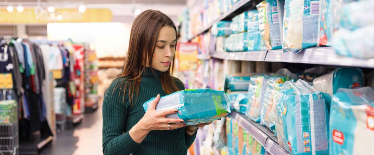 Woman buys diapers for child at the supermarket, portrait of young mother in shop mall