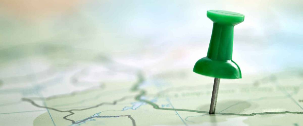Pushpin showing the location of a destination point on a green map