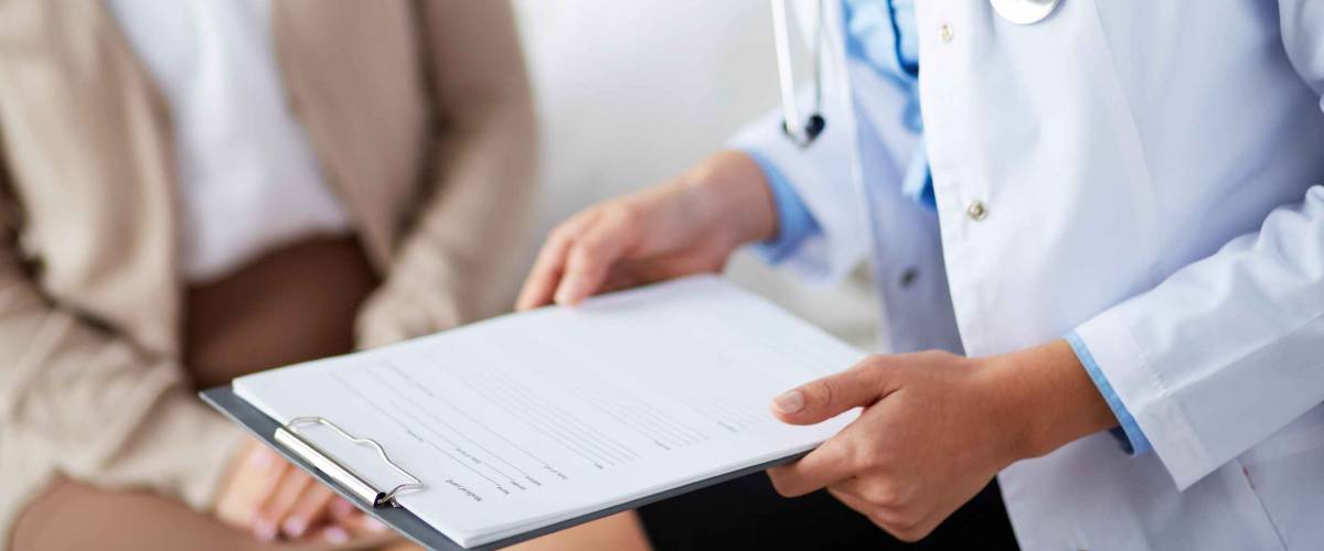 Female doctor holding application form while consulting patient
