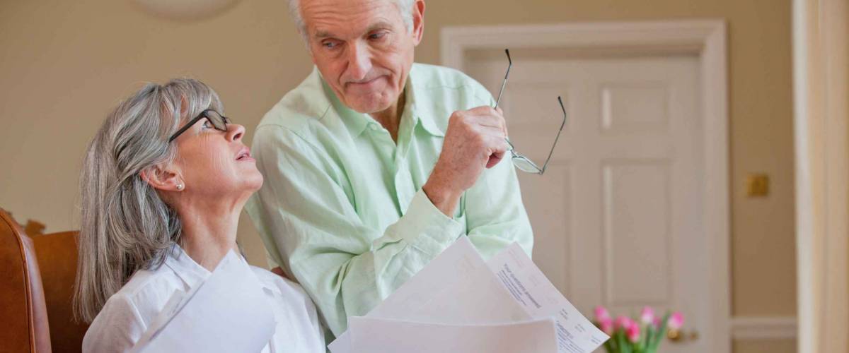Horizontal shot of a senior couple discussing paperwork with the woman holding documents looks at her husband.