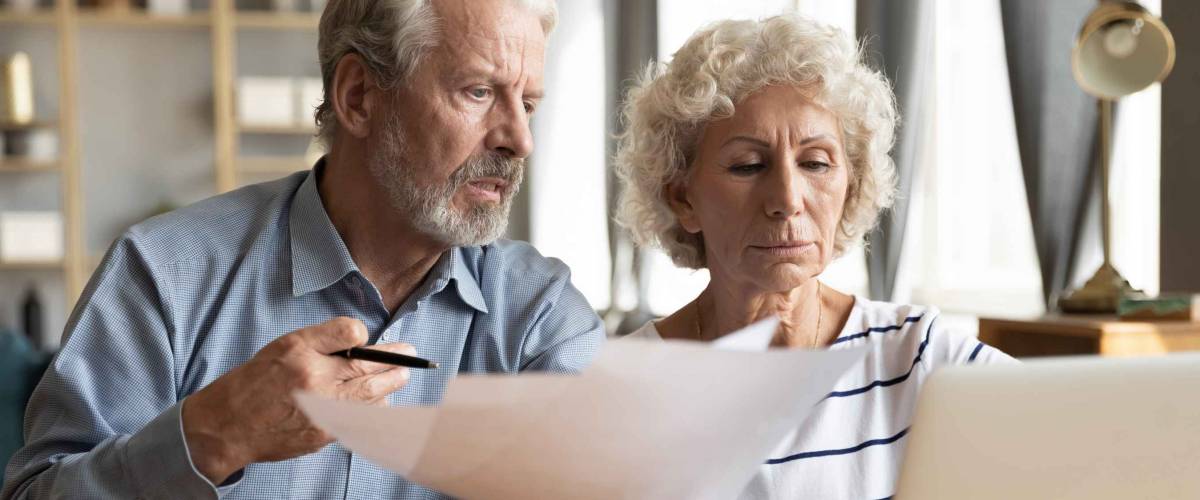 Stressed elderly married couple paying taxes