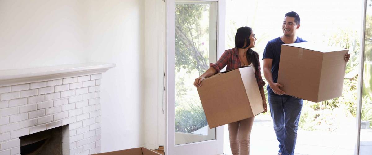 Couple Carrying Boxes Into New Home On Moving Day
