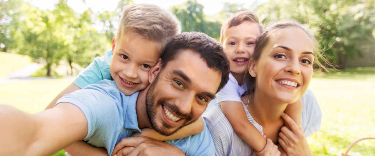 happy mother, father and two little sons having picnic and taking selfie at summer park