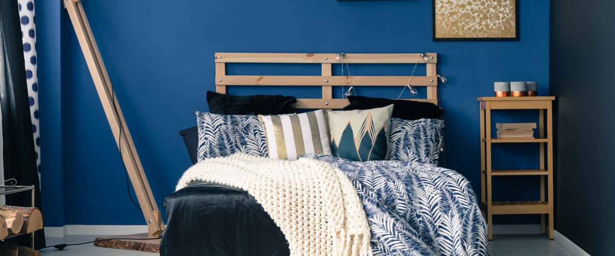 Stylish bedroom interior with dark blue wall