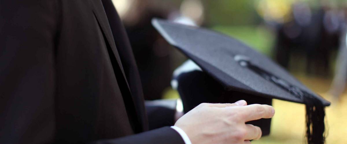 Man holding a mortar board in focus on a autumn day in Oxford