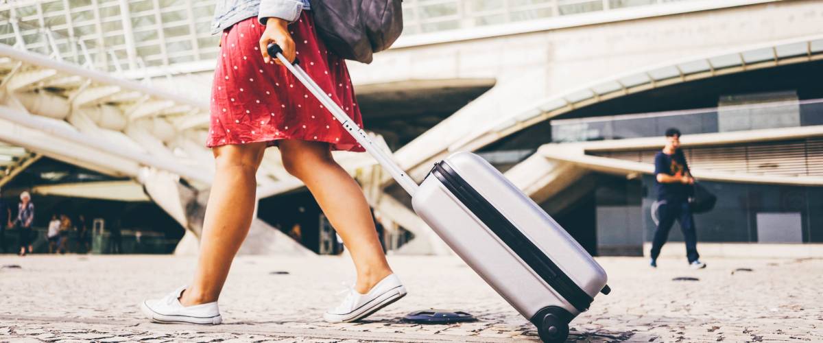 Woman with rolling suitcase, travelling abroad