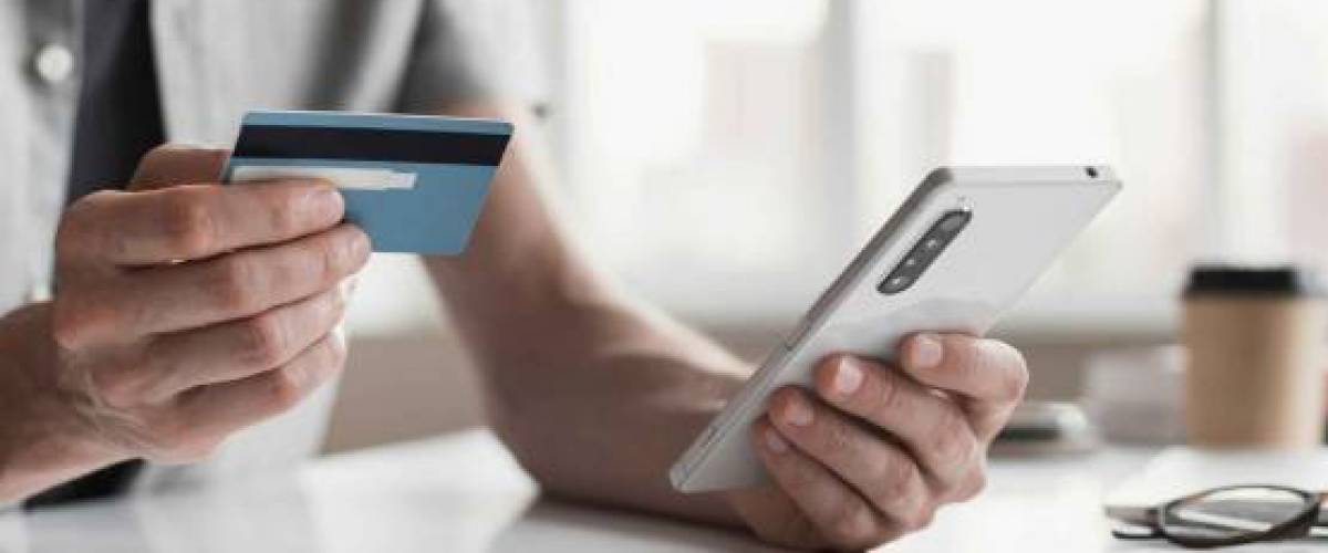 Man paying online with credit card and smartphone at home.