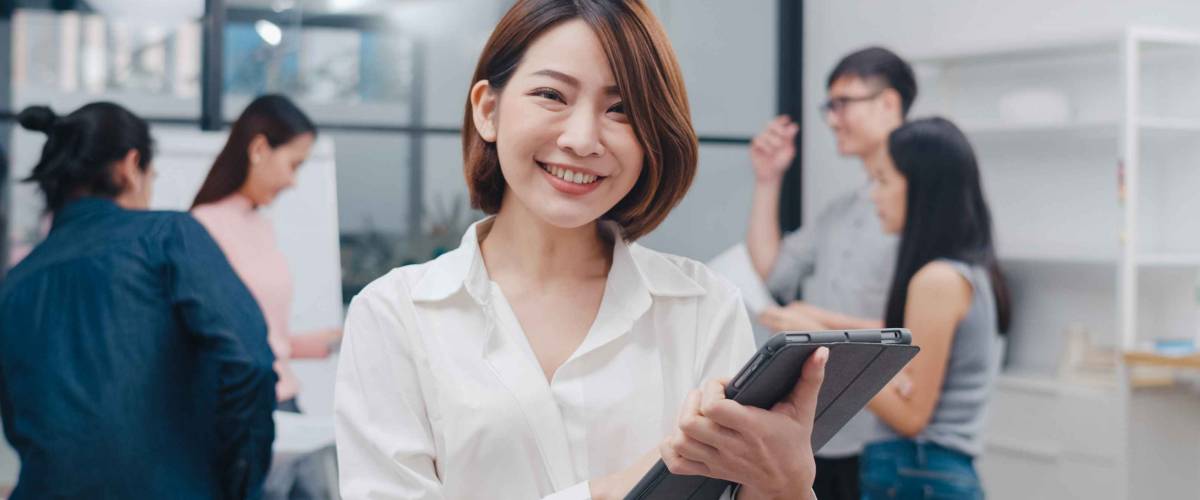 Business woman smiling and holding a tablet in the office