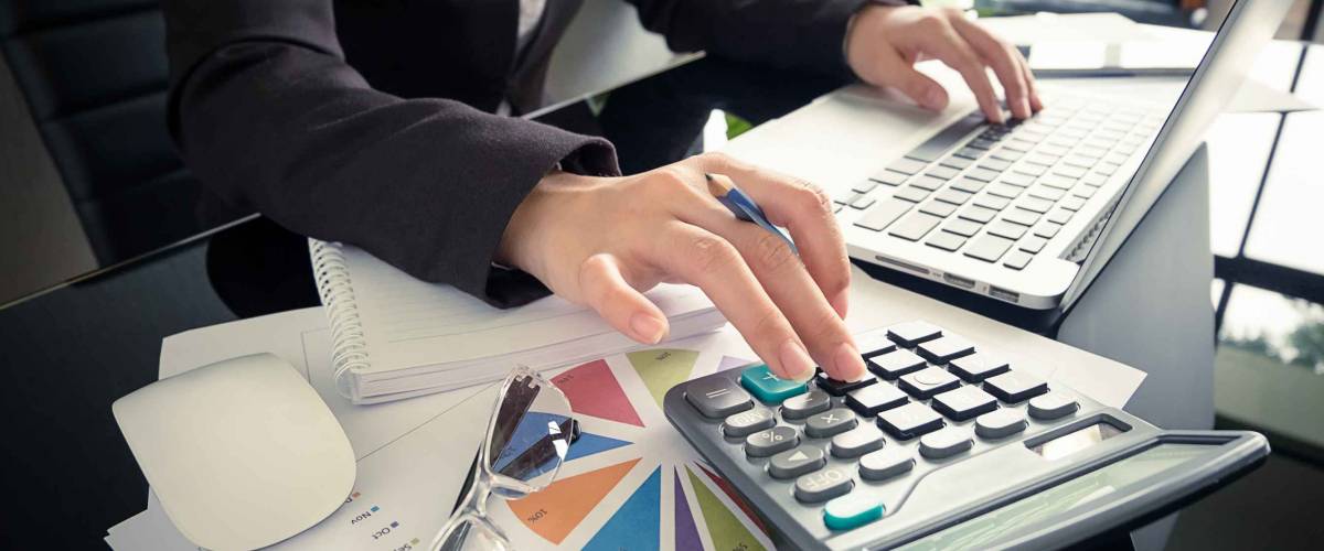 Business woman using a calculator to calculate the numbers on his desk in a office.