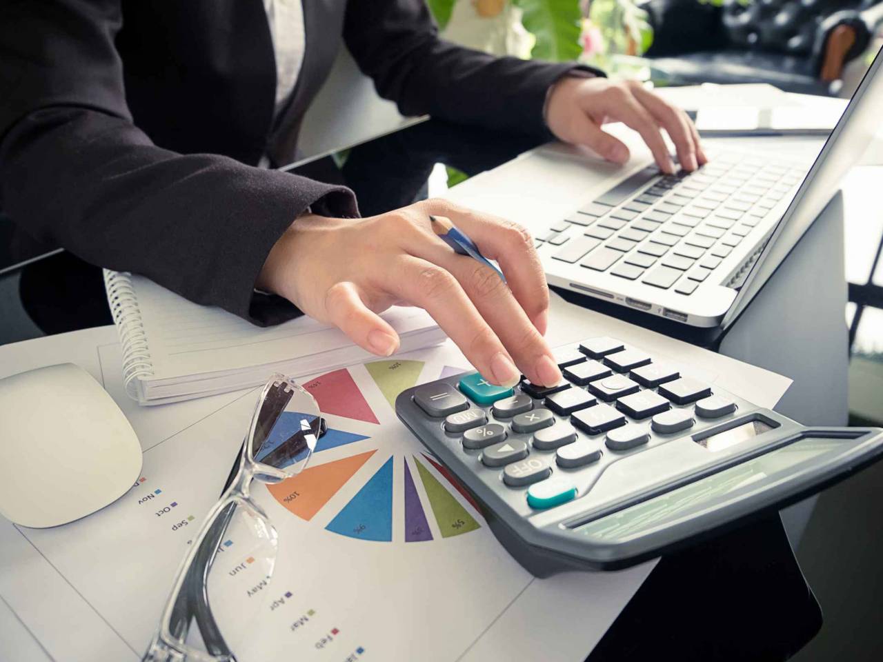 Business woman using a calculator to calculate the numbers on his desk in a office.