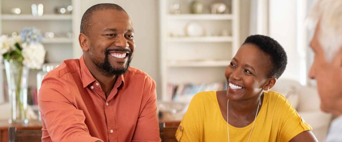 Mature black husband shaking hands with senior agent on taking loan.