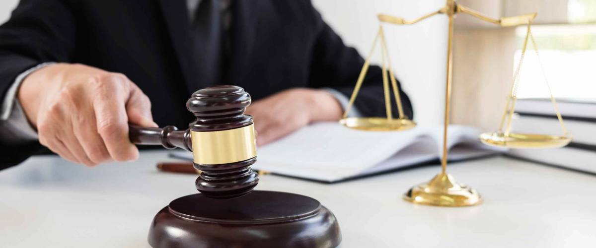 Close up of Male lawyer or judge hand's striking the gavel on sounding block, working with Law books, report the case on table in modern office, Law and justice concept.