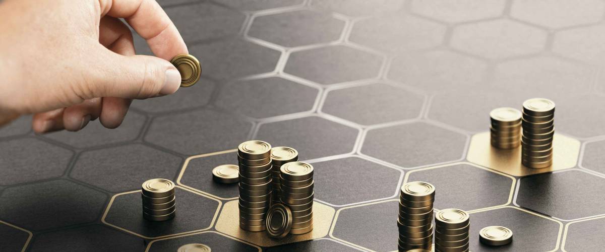 Human hand stacking coins over a black background with hexagonal golden shapes.