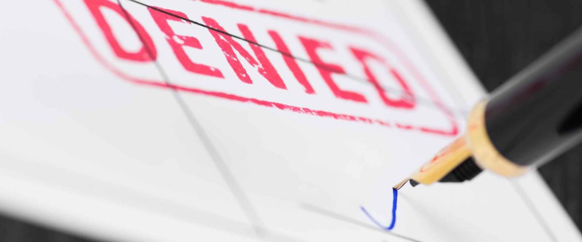 Seal denied stamped on a document and fountain pen. Macro shot. Soft focus.
