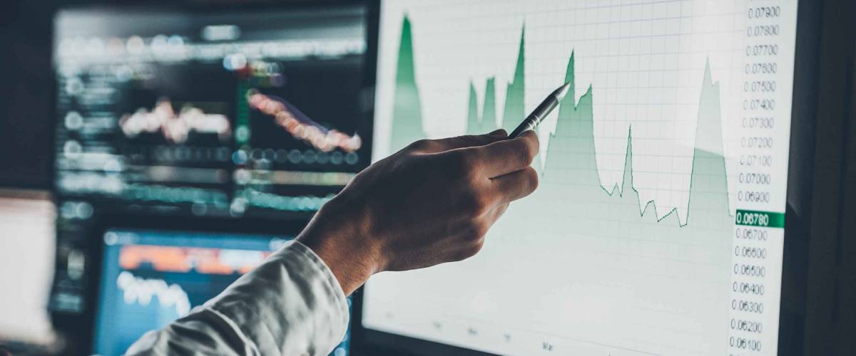 Analyzing data. Close-up of young businessman pointing on the data presented in the chart with pen while working in creative office