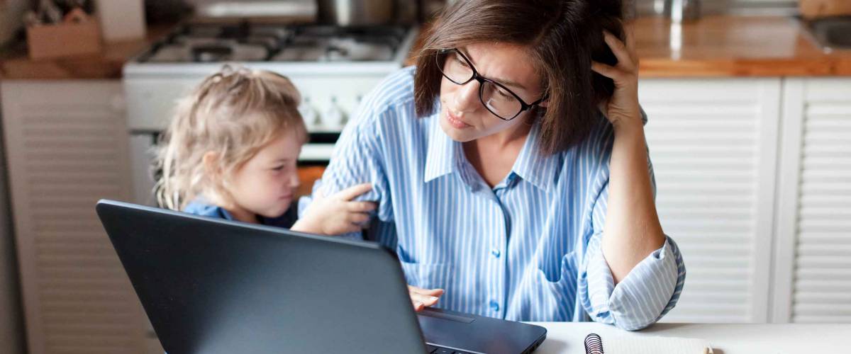 Working mother in home office, worried about finance