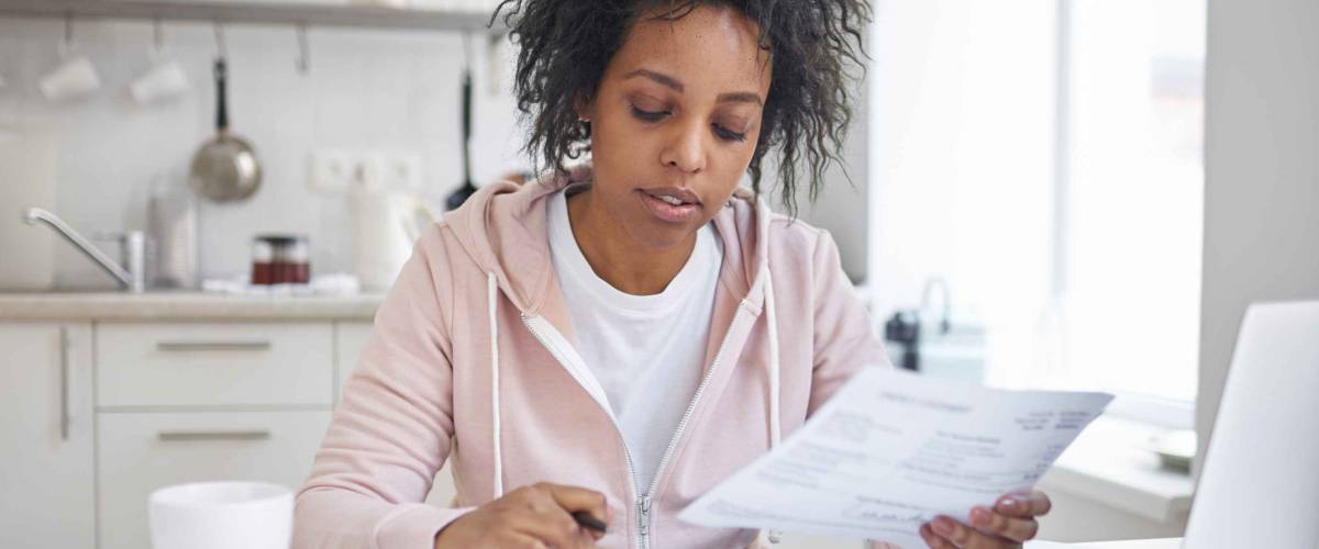Woman working on financial literacy, calculator and documents at kitchen table