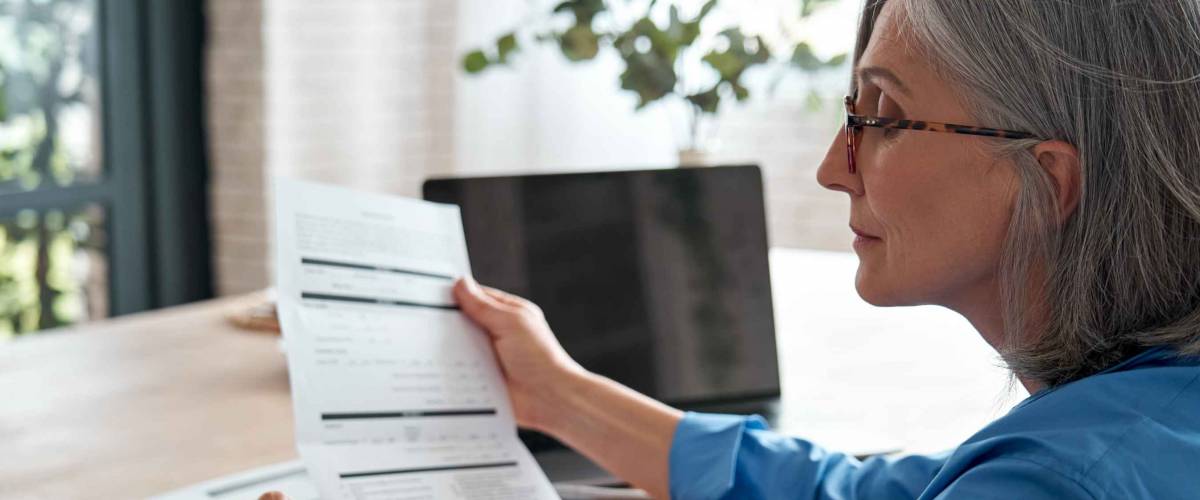 Older woman looks at bills and calculates finances